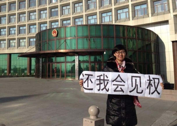 L'avvocato cinese per i diritti civili Wang Yu con uno striscione che dice "Restituisci il mio diritto di vedere i clienti". (Democratic China)