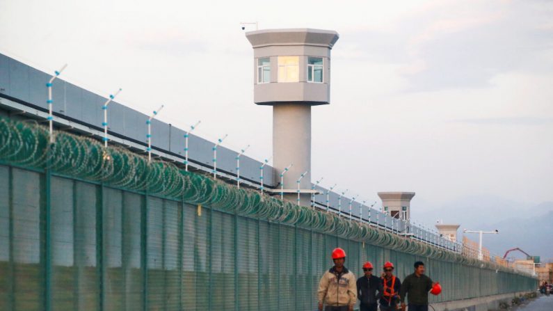 Operai lungo alla recinzione di quello che è ufficialmente noto come un centro di istruzione delle competenze professionali a Dabancheng,  Xinjiang (foto: Thomas Peter/Reuters/File Photo).