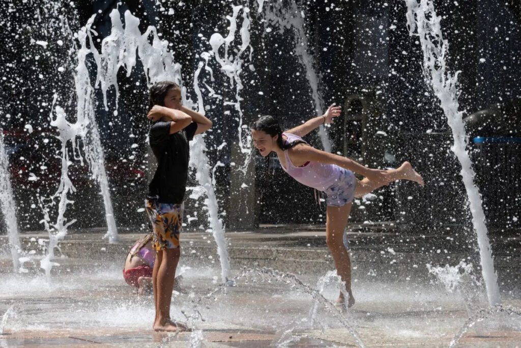 Le sorelle Olivia, 10 anni, ed Evelyn Black, 12 anni, giocano nelle fontane Gateway del parco Discovery Green per sfuggire al caldo torrido di Houston, Texas, il 18 luglio 2023. (Adrees Latif/Reuters)