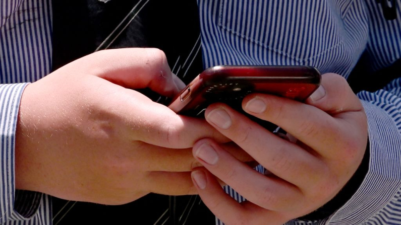 A schoolboy looks at his phone in Melbourne on November 27, 2024 as Australia looks to ban children under 16 from social media with claims social media platforms have been tarnished by cyberbullying, the spread of illegal content, and election-meddling claims. Australia is among the vanguard of nations trying to clean up social media, and the age limit legislation will make it among world's strictest measures aimed at children. (Photo by William WEST / AFP) (Photo by WILLIAM WEST/AFP via Getty Images)