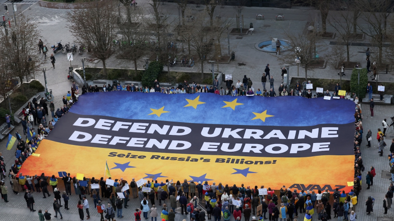 Attivisti ucraini espongono un enorme striscione a Bruxelles, in Belgio, il 5 marzo 2025, esortando i leader europei a confiscare i beni russi congelati per finanziare l'Ucraina nel suo conflitto contro la Russia (foto: Reuters/Yves Herman).