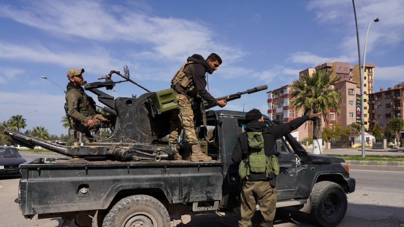 Un membro delle forze siriane è in piedi su un veicolo militare mentre le forze di sicurezza siriane combattono contro un'insurrezione nascente da parte di combattenti della setta alawita dell'ex leader deposto Bashar al Assad, a Latakia, Siria, 7 marzo 2025 (Reuters/Karam al-Masri).